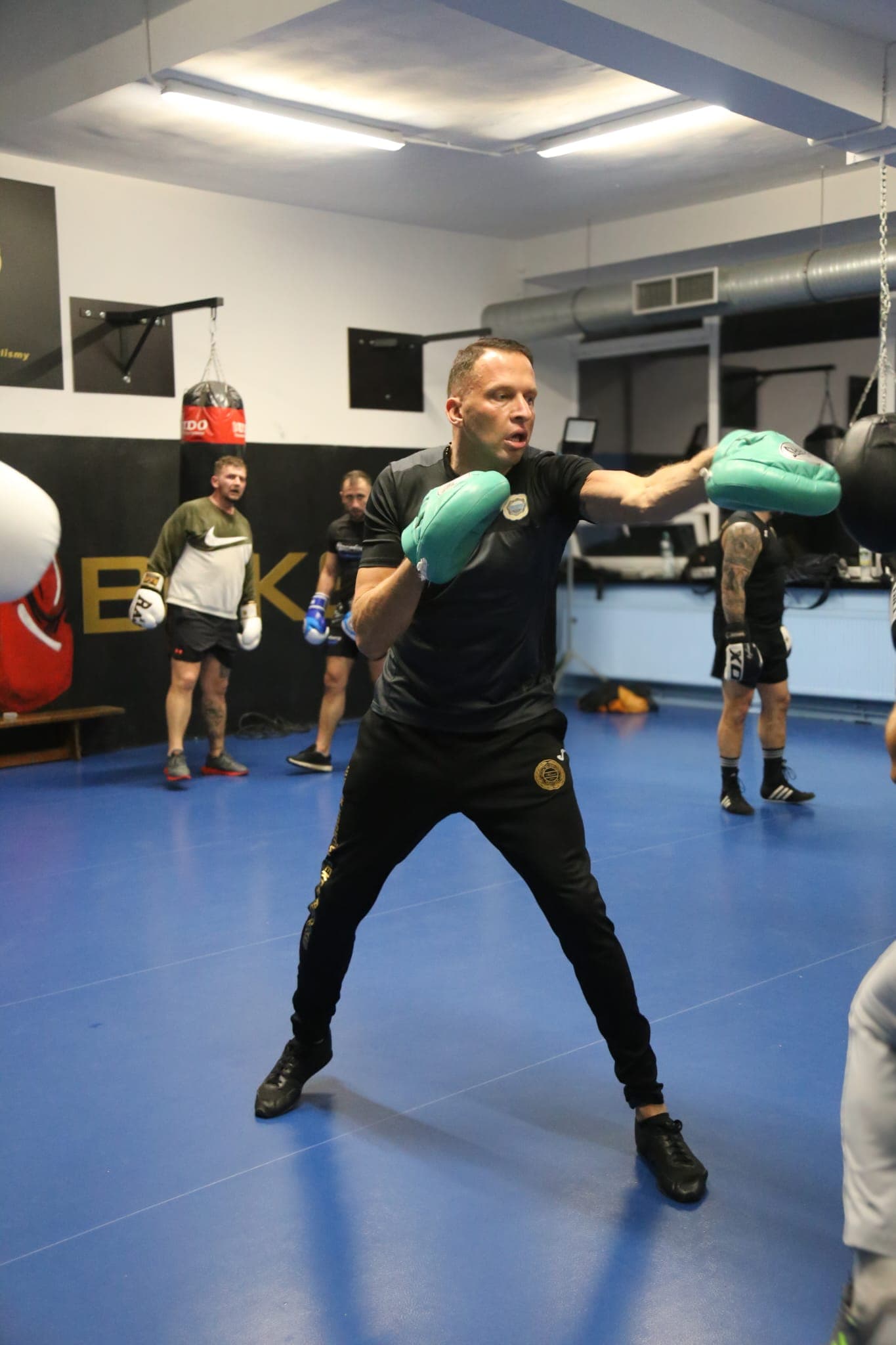 Trening grupowy boksu — Sławomir Moskal z łapami trenerskimi